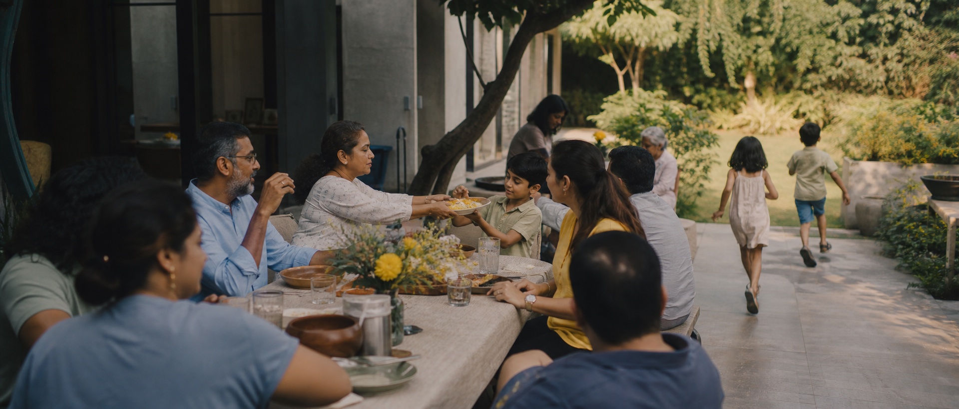 Several generations of families sharing an outdoor meal while children explore the garden